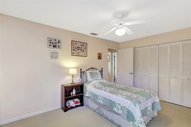 bedroom with visible vents, a ceiling fan, a closet, baseboards, and light colored carpet