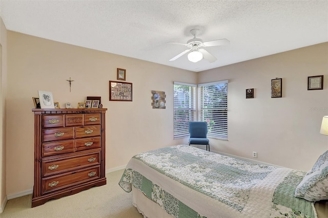 bedroom featuring light carpet, a textured ceiling, baseboards, and a ceiling fan