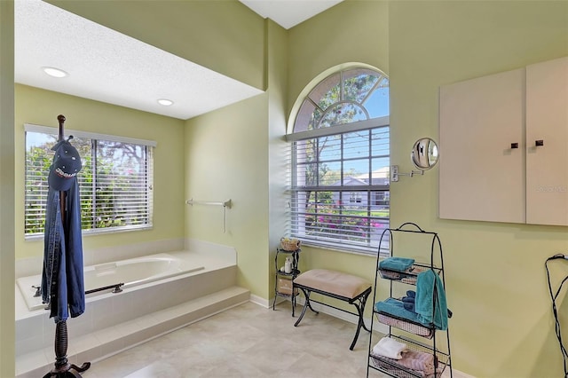 bathroom featuring baseboards, a garden tub, and a textured ceiling