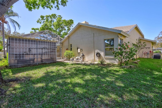 back of house featuring central air condition unit, a lawn, and stucco siding