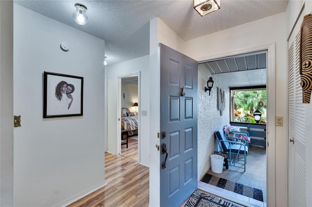 entryway featuring light wood-style floors and a textured ceiling