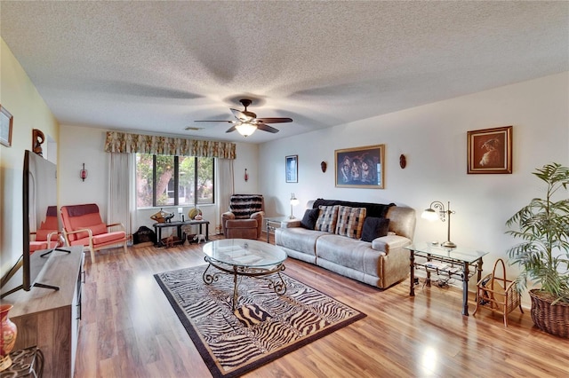 living area featuring ceiling fan, a textured ceiling, and wood finished floors