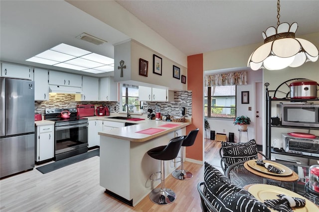 kitchen with a peninsula, light countertops, visible vents, and appliances with stainless steel finishes