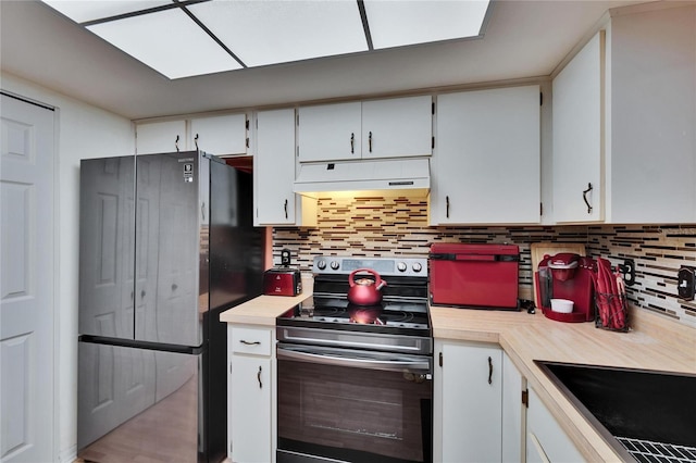 kitchen with freestanding refrigerator, light countertops, under cabinet range hood, and electric range oven