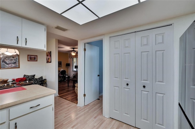 kitchen with visible vents, a ceiling fan, white cabinets, light wood finished floors, and light countertops