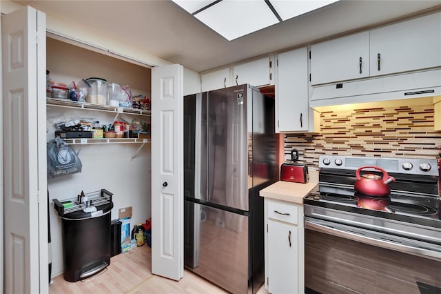 kitchen featuring under cabinet range hood, backsplash, white cabinetry, stainless steel appliances, and light countertops