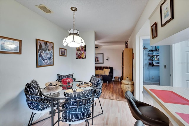 dining area featuring visible vents, a textured ceiling, and wood finished floors