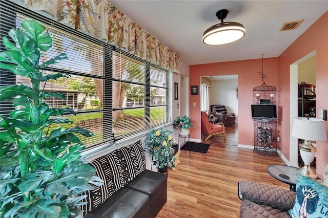 living area with baseboards, visible vents, and light wood-type flooring