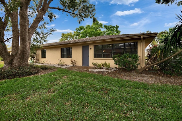 rear view of property featuring stucco siding and a lawn