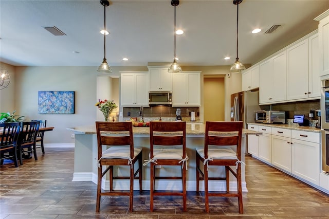 kitchen with visible vents, backsplash, baseboards, appliances with stainless steel finishes, and white cabinetry