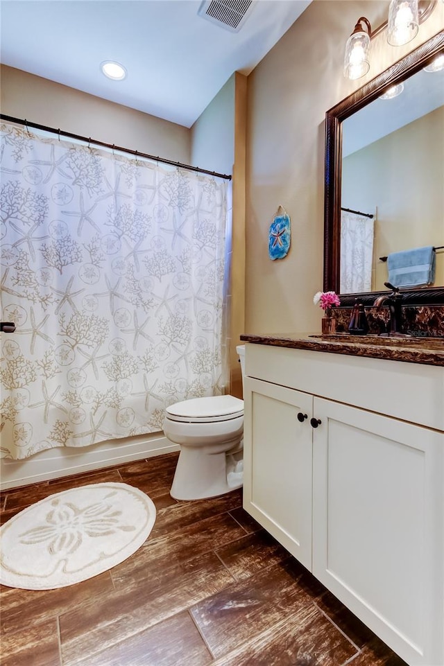 bathroom featuring visible vents, toilet, wood finished floors, a shower with shower curtain, and vanity