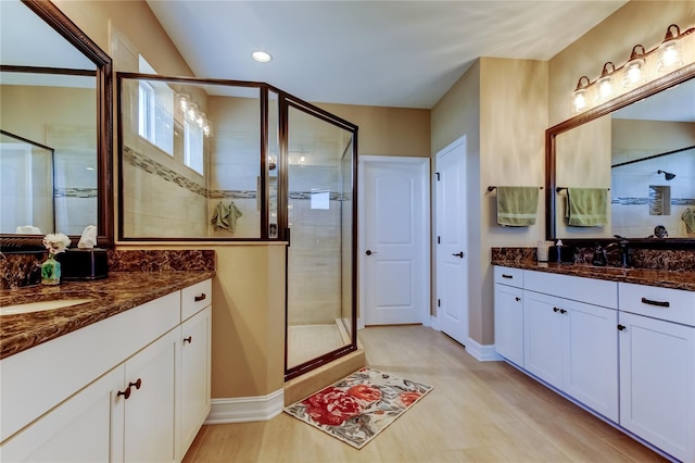 bathroom featuring a sink, two vanities, and a stall shower