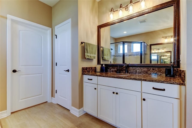 full bathroom with vanity, a shower stall, baseboards, and visible vents