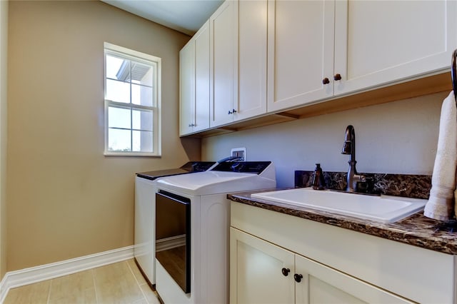 laundry room with a sink, baseboards, cabinet space, and washing machine and dryer