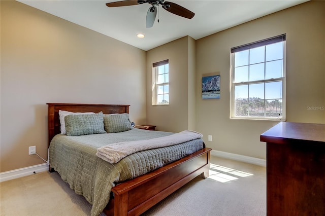 bedroom with multiple windows, light carpet, and baseboards