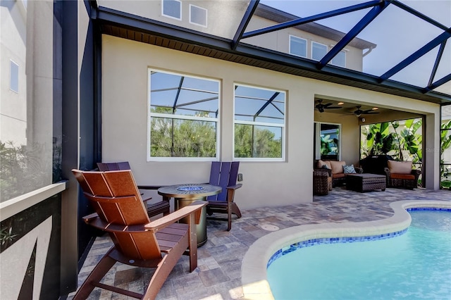 outdoor pool featuring glass enclosure, a patio, a ceiling fan, and an outdoor hangout area