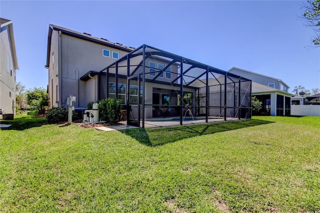 rear view of property with glass enclosure, a patio, a yard, and stucco siding