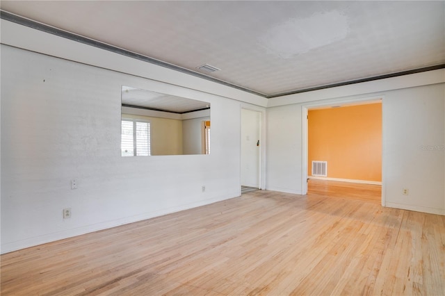 empty room featuring wood finished floors, visible vents, and baseboards