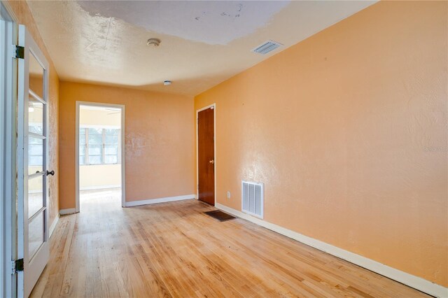 empty room with light wood-style flooring, baseboards, and visible vents