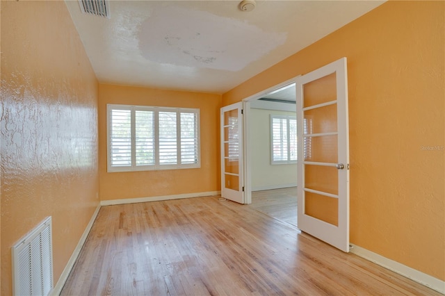 spare room featuring visible vents, baseboards, wood finished floors, and french doors