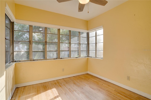 empty room with hardwood / wood-style floors, a ceiling fan, and baseboards