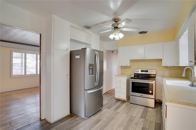 kitchen featuring visible vents, a sink, stainless steel appliances, light countertops, and light wood-style floors