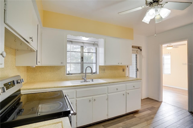 kitchen with tasteful backsplash, stainless steel electric range oven, light countertops, and a sink