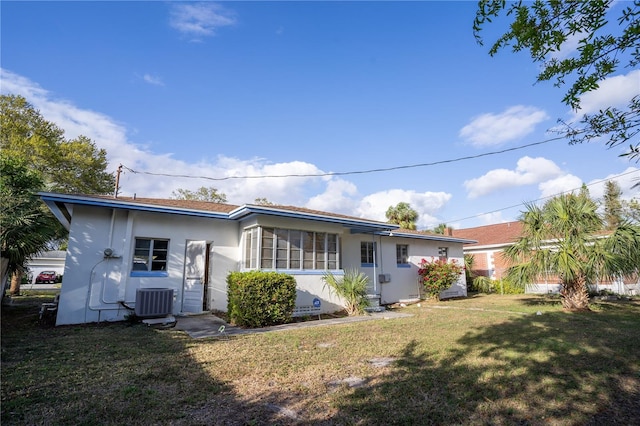 back of property with central air condition unit, a yard, and stucco siding