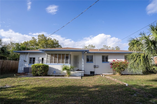 rear view of house featuring stucco siding, a yard, and fence