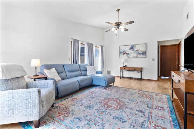 living room featuring a textured ceiling, wood finished floors, visible vents, and ceiling fan