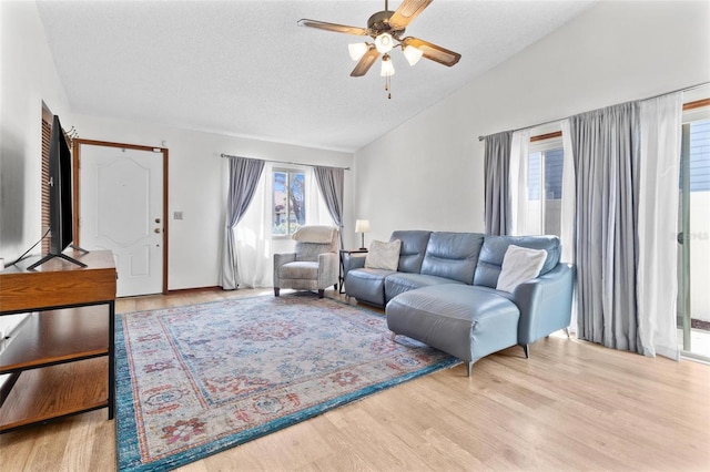 living room with ceiling fan, a textured ceiling, wood finished floors, and vaulted ceiling