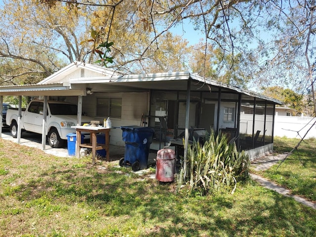 view of side of property with a carport, fence, and a sunroom