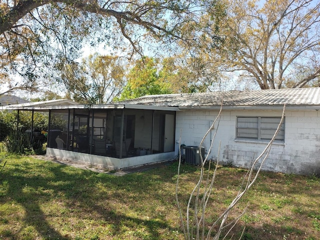 view of property exterior featuring concrete block siding, cooling unit, a yard, a sunroom, and metal roof