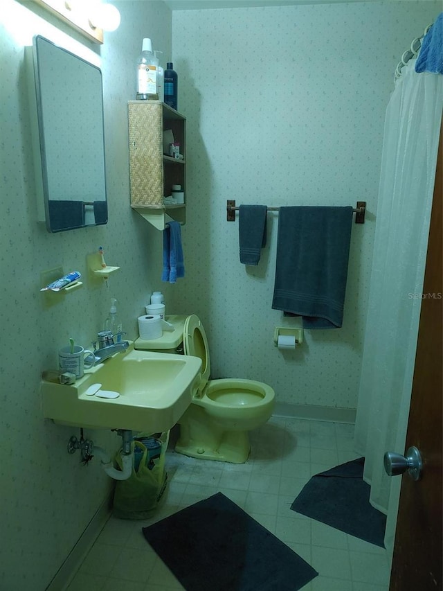 full bath featuring a sink, wallpapered walls, toilet, and tile patterned flooring