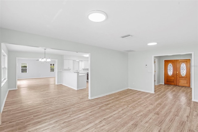 unfurnished living room with light wood-type flooring, visible vents, and baseboards