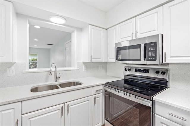 kitchen with recessed lighting, a sink, stainless steel appliances, white cabinetry, and backsplash