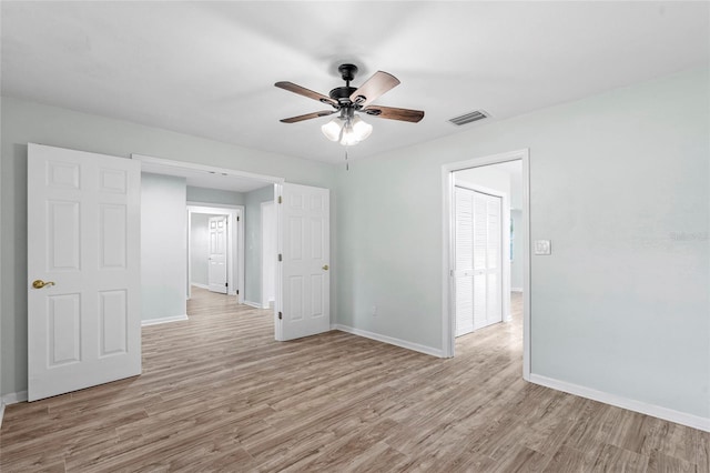 unfurnished room featuring ceiling fan, wood finished floors, visible vents, and baseboards