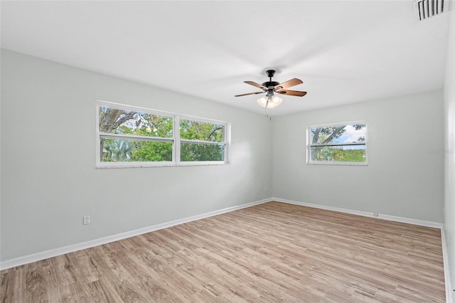 empty room featuring light wood-style floors, baseboards, and a wealth of natural light