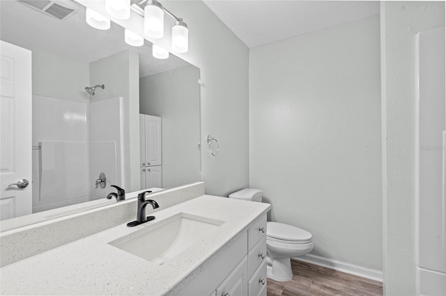 bathroom with vanity, wood finished floors, visible vents, walk in shower, and toilet