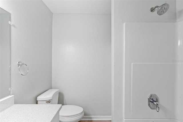 bathroom with vanity, wood finished floors, baseboards, a shower, and toilet