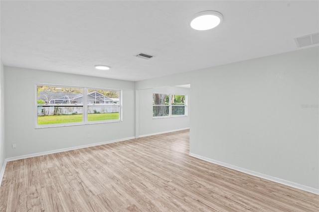 empty room with visible vents, baseboards, and light wood-type flooring