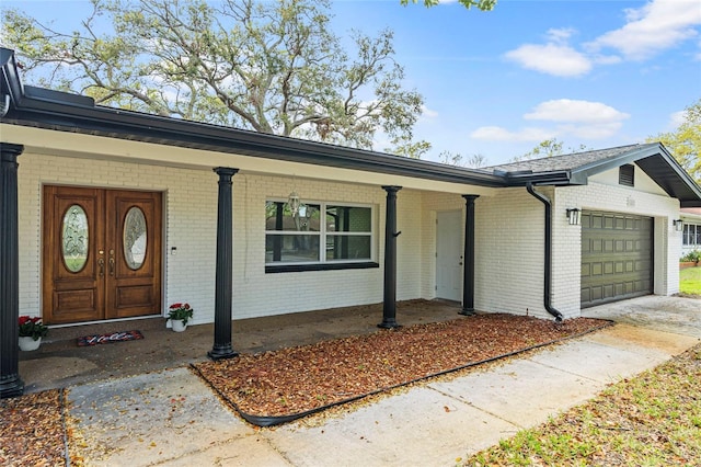 view of front of home with driveway, brick siding, covered porch, and an attached garage