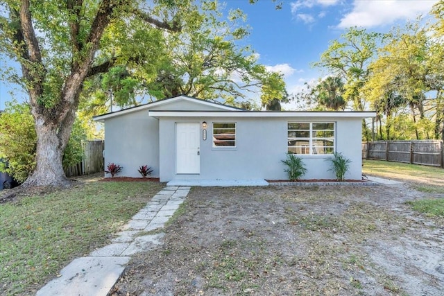 view of front of property with stucco siding, a front yard, and fence