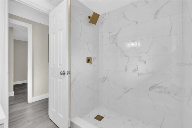 bathroom featuring tiled shower, baseboards, and wood finished floors