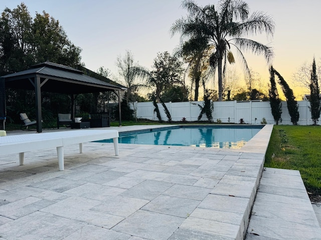 pool at dusk featuring a gazebo, a fenced in pool, a patio, and fence