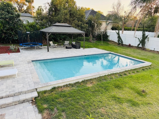 view of swimming pool with a fenced in pool, a trampoline, a gazebo, a lawn, and a patio area