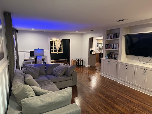 living room featuring visible vents, dark wood finished floors, recessed lighting, wainscoting, and arched walkways