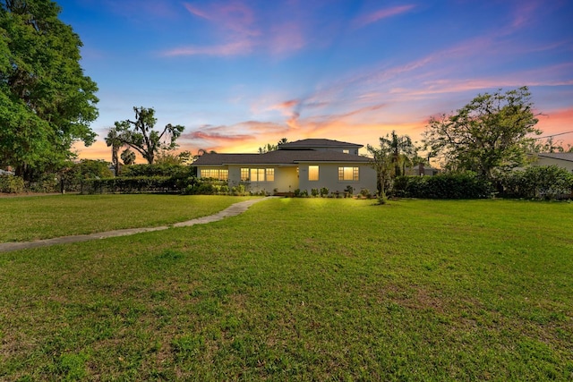 back of property featuring stucco siding and a yard