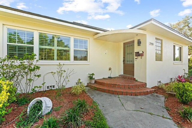 entrance to property featuring crawl space and stucco siding
