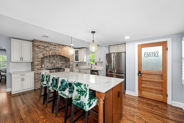 kitchen featuring a kitchen island, a sink, stainless steel appliances, and dark wood finished floors